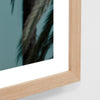 Wooden picture frame with a blurred artwork of green foliage on a light gray background