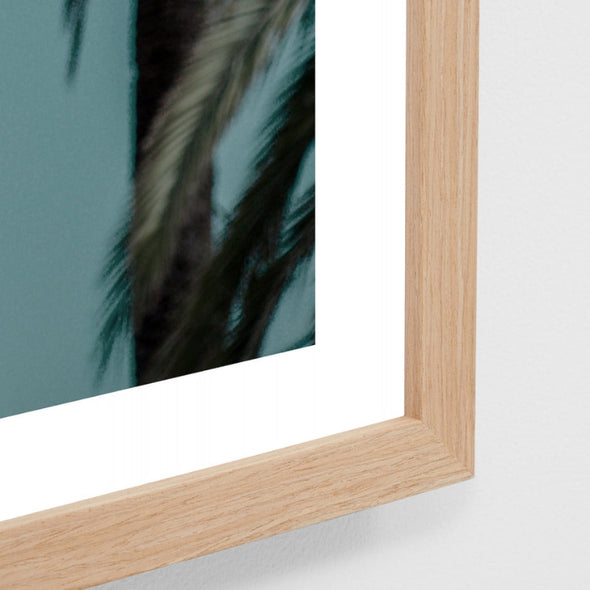 Wooden picture frame with a blurred artwork of green foliage on a light gray background