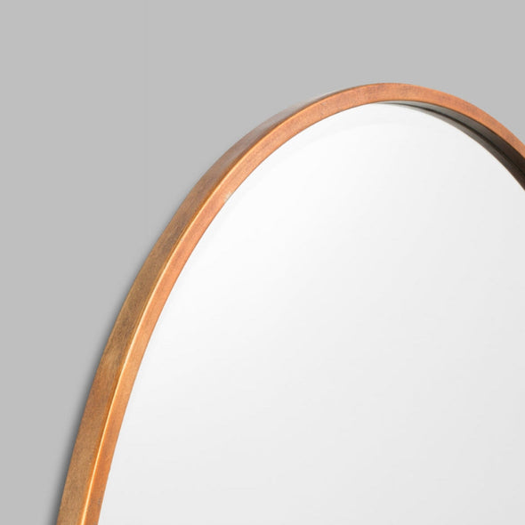 Round mirror with a copper frame on a grey background