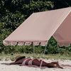 Person sunbathing under a large pink beach umbrella on a sandy beach with greenery in the background.