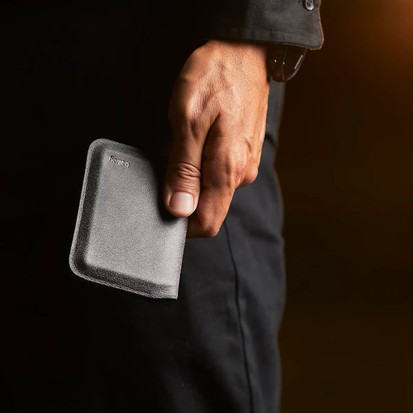 Hand holding a gray wallet with a blurred background