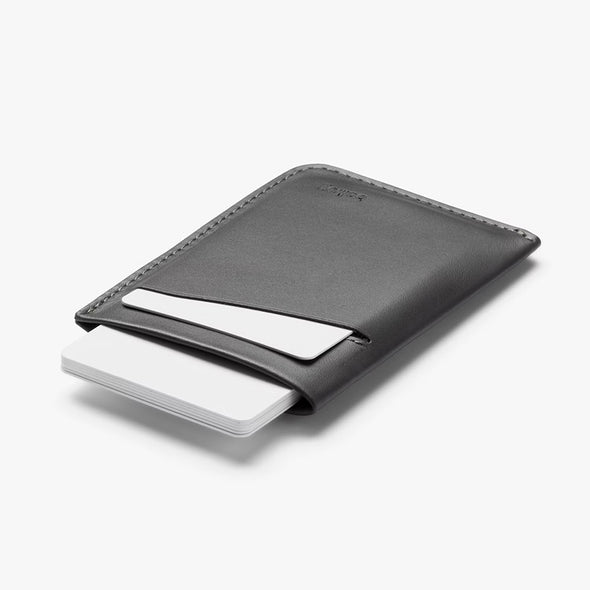 Black leather cardholder with a white card on a light gray background