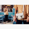 Person wearing a beige shirt with a white crossbody bag in a diner setting