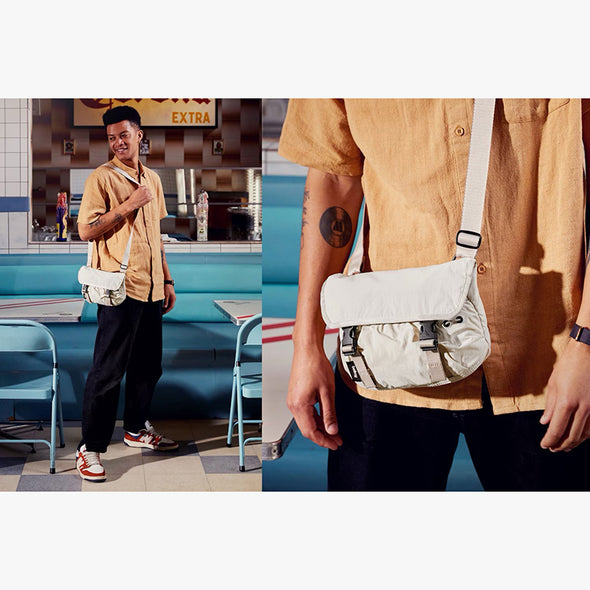 Person wearing a beige shirt with a white crossbody bag in a diner setting
