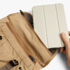 Beige travel organizer with a compartment for a tablet or book, held by a hand.