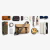 Collection of travel accessories including a beige bag, phone case, and various small items on a white background