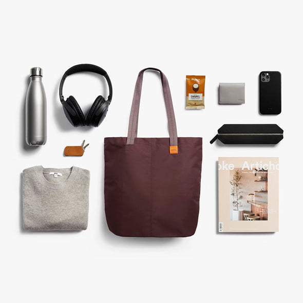 Collection of everyday items including a tote bag, phone, water bottle, and clothing on a white background