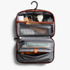 Open toiletry bag with various travel items on a white background