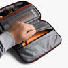 Hand opening a pocket in a toiletry case with a white background