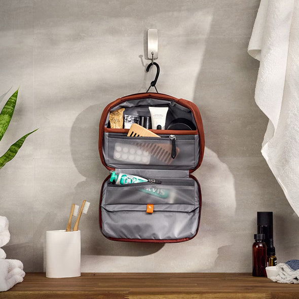 Open toiletry bag with travel items on a bathroom shelf