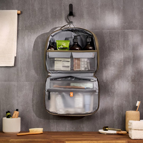 Gray toiletry bag with products on a gray wall background