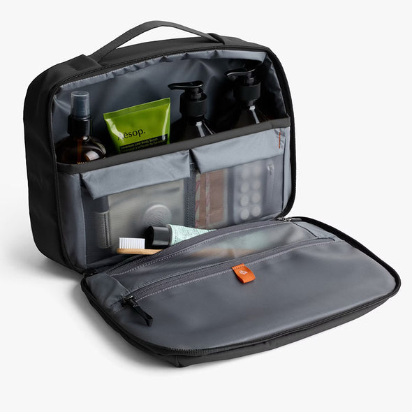 Open toiletry bag with travel-sized products on a light gray background