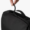 Black toiletry bag with a hand holding onto the handle against a white background
