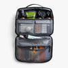 Open toiletry bag with various items on a light gray background