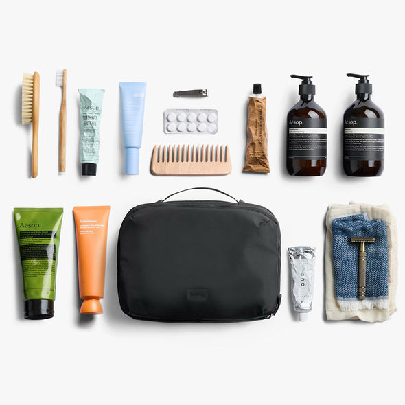 Collection of grooming products including bottles, tubes, and a black toiletry bag on a white background.