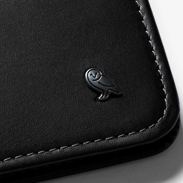 Close-up of a black leather product with a brand logo on a light gray background