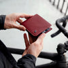 Person holding a red leather wallet with a blurred background