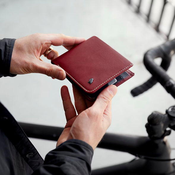 Person holding a red leather wallet with a blurred background