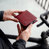 Person holding a red wallet with a blurred background of a bicycle