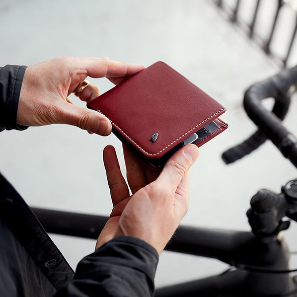 Person holding a red wallet with a blurred background of a bicycle