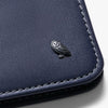 Close-up of a navy blue leather wallet with an owl emblem on a light gray background