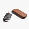 Brown leather key case with a black key fob on a white background