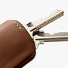 Brown leather key fob with metallic key on a white background