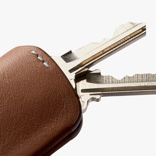 Brown leather key fob with metallic key on a white background