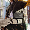 Person sitting on a box with a black crossbody bag in an urban setting