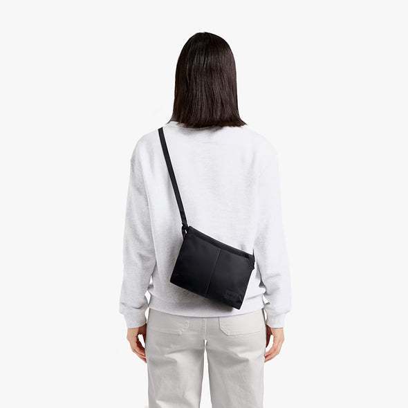 Person wearing a black crossbody bag on a white background