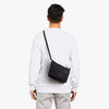 Person wearing a black crossbody bag on a white background