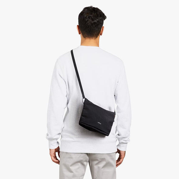 Person wearing a black crossbody bag on a white background