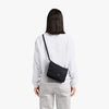 Person wearing a black crossbody bag on a white background