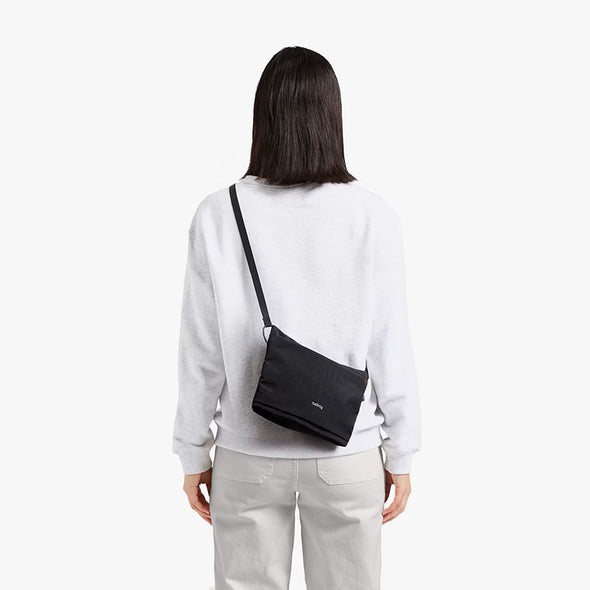 Person wearing a black crossbody bag on a white background