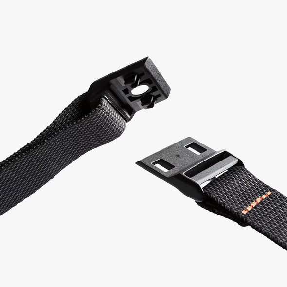 Two black webbing straps with plastic buckles on a white background