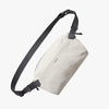 Light gray sling bag with black strap on a white background