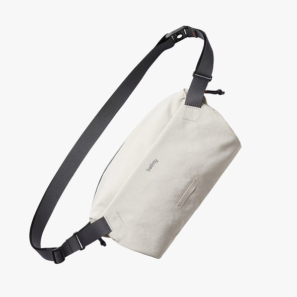 Light gray sling bag with black strap on a white background