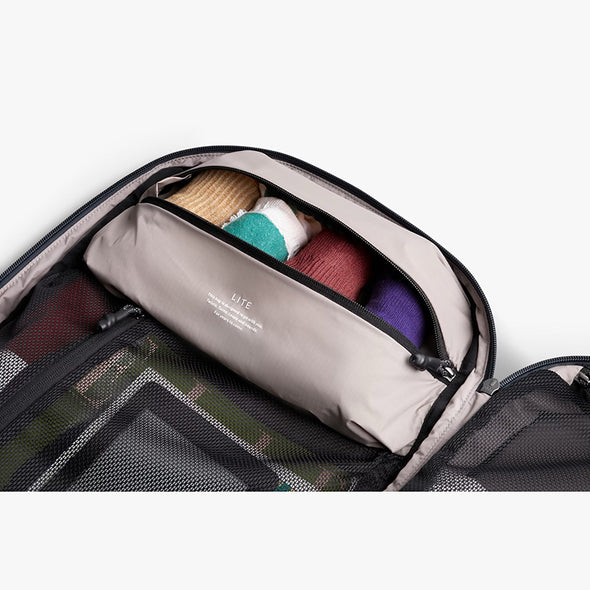 Open suitcase with travel items including a brush and bottles on a white background