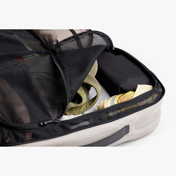 Open suitcase with clothes and a hat inside on a white background