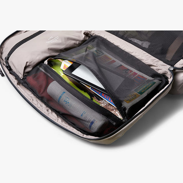 Open backpack with compartments containing a smartphone, magazine, and other items on a white background