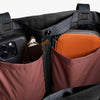 Close-up of a bag with compartments containing a phone, sunglasses, and a wallet.