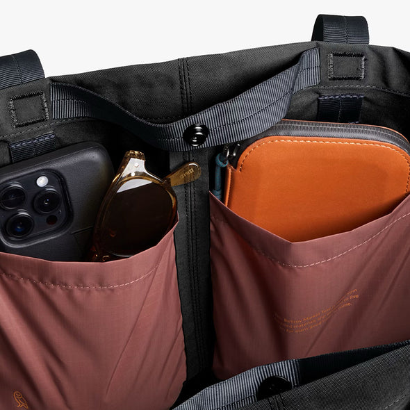 Close-up of a bag with compartments containing a phone, sunglasses, and a wallet.