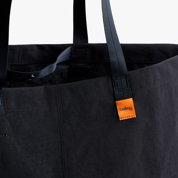 Black tote bag with orange tag featuring 'bellroy' brand on a white background