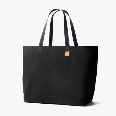 Black tote bag with a small orange label on a white background