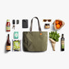 Green tote bag surrounded by various items on a white background