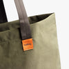 Green tote bag with a brown strap and 'bellroy' logo on a white background