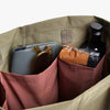 Green bag with compartments containing a phone, wallet, and bottle.