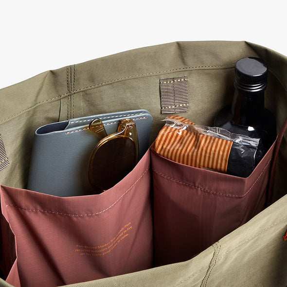 Green bag with compartments containing a phone, wallet, and bottle.