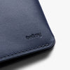 Close-up of a blue leather wallet with 'bellroy' branding on a light gray background