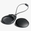 Black mesh screen and round black object with a string on a white background